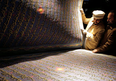 الخطاط الأفغاني مع نسخته الأكبر في العالم من القرآن الكريم